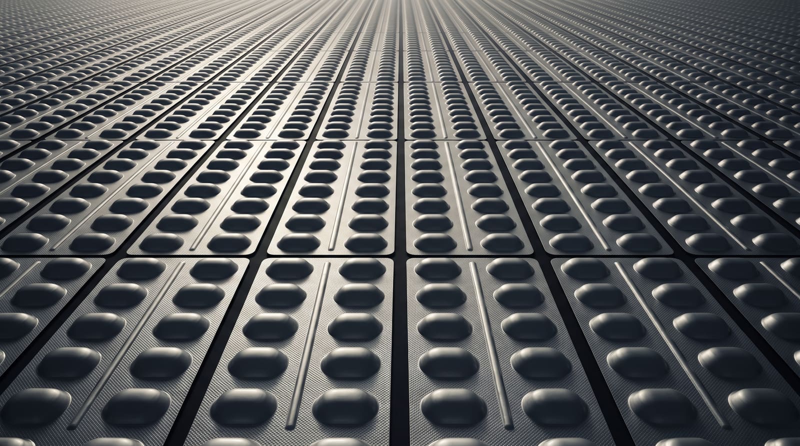 An overhead field of unprinted aluminium pharmaceutical strip-pack foil repeating to a distant vanishing point.