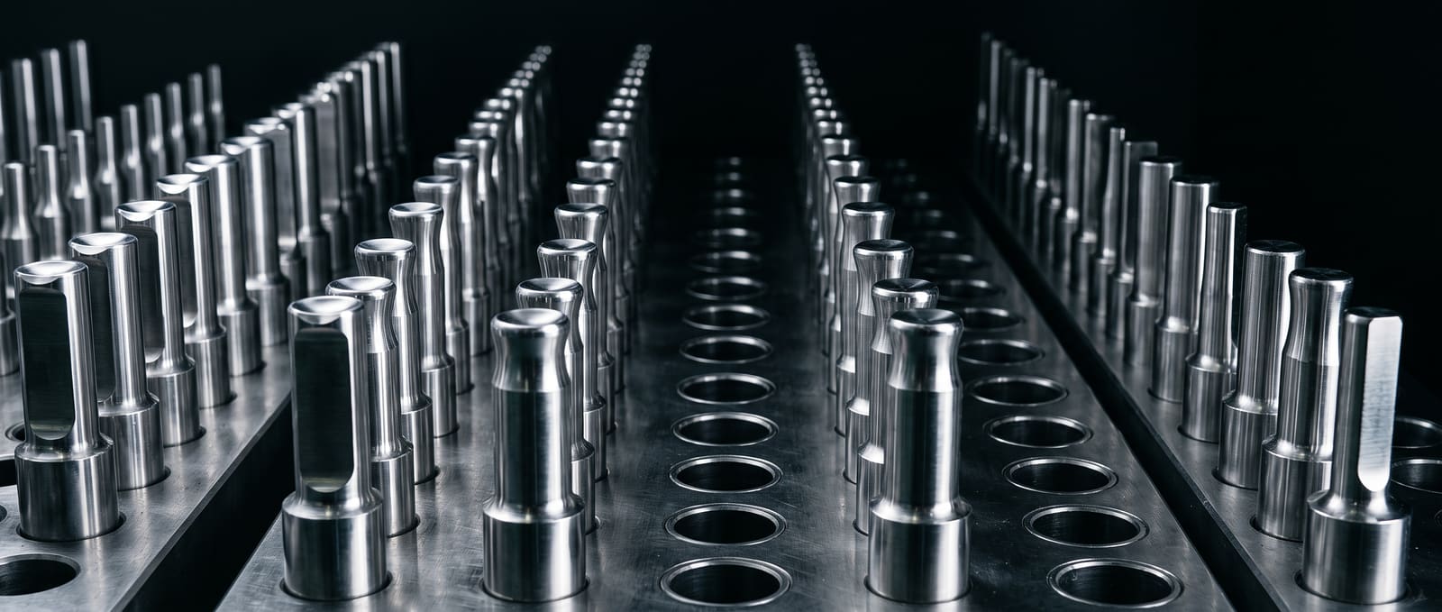 Rows of polished stainless steel tablet compression punches and dies in precise repetition.